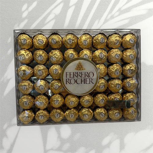 Box of Ferrero Rocher chocolates with a clear lid on a light background