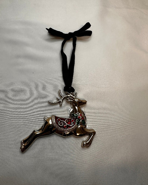 Decorative horse-shaped brooch with black ribbon on a light gray background