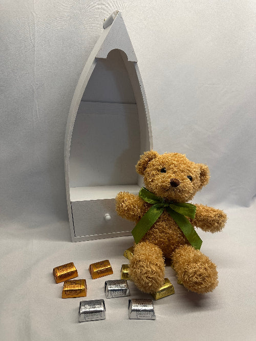 Teddy bear with a green ribbon on a boat-shaped mirror with decorative items on a white background
