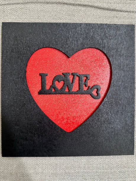 Red heart-shaped cutout with 'LOVE' text on a black background