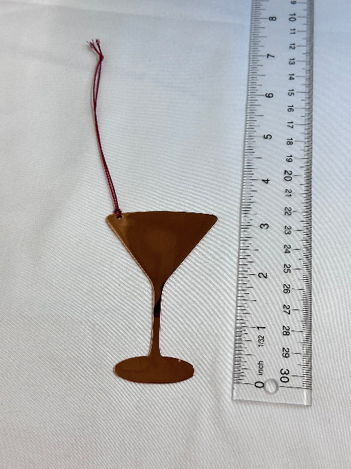 Metallic object with a string next to a ruler on a white background