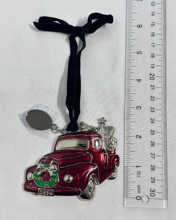 Red and silver car with a wreath design on a white surface, next to a ruler for scale.