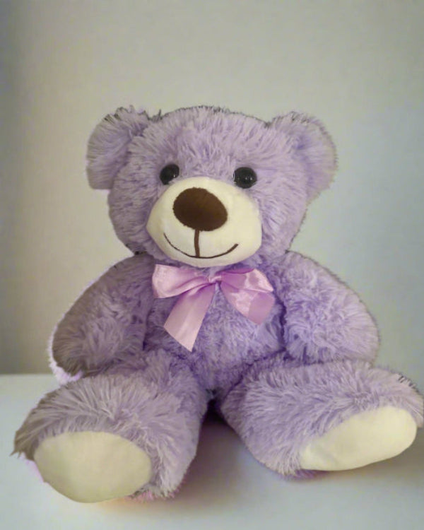 Purple teddy bear with a pink bow on a white background