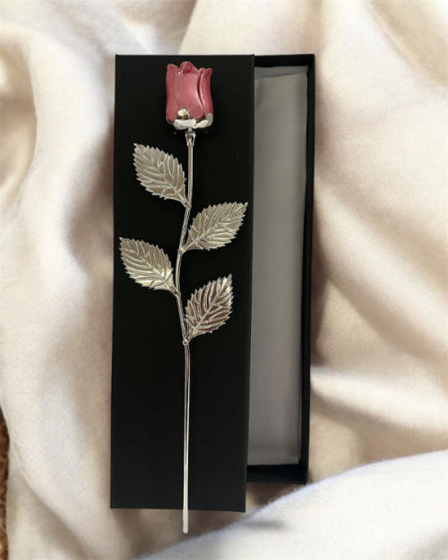 Silver rose brooch with pink rosebud in a black box on a soft fabric background