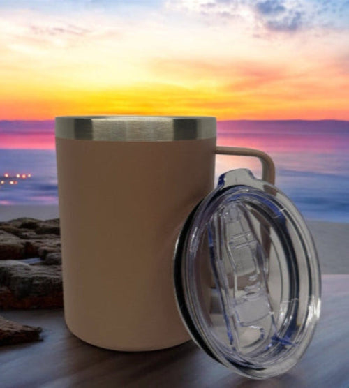 Pink insulated mug with a clear lid on a wooden surface at sunset by the beach.