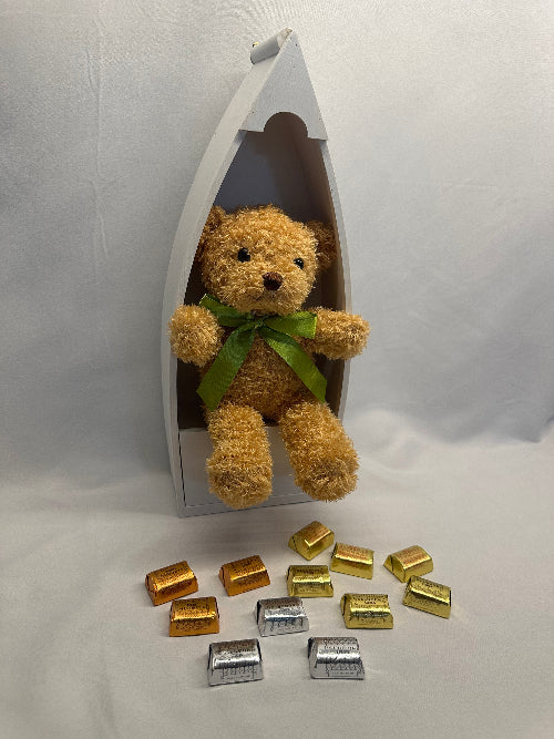 Teddy bear in a boat with decorative items on a white background