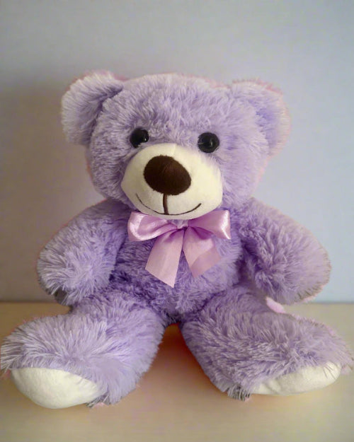 Purple teddy bear with a pink bow on a light background