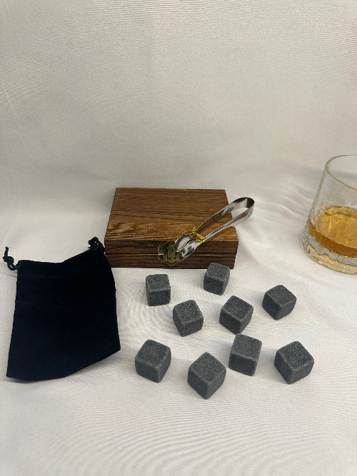Set of gray stones with a wooden container and black pouch on a white background
