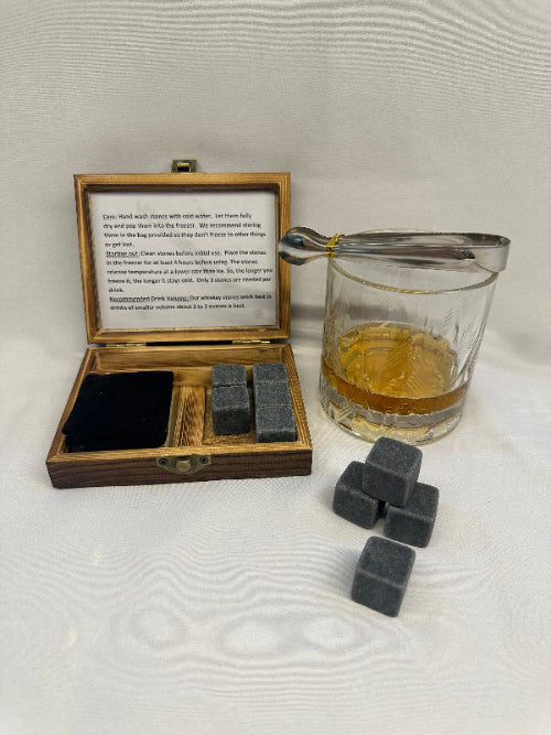 Whiskey stones with a wooden box and glass of whiskey on a textured surface