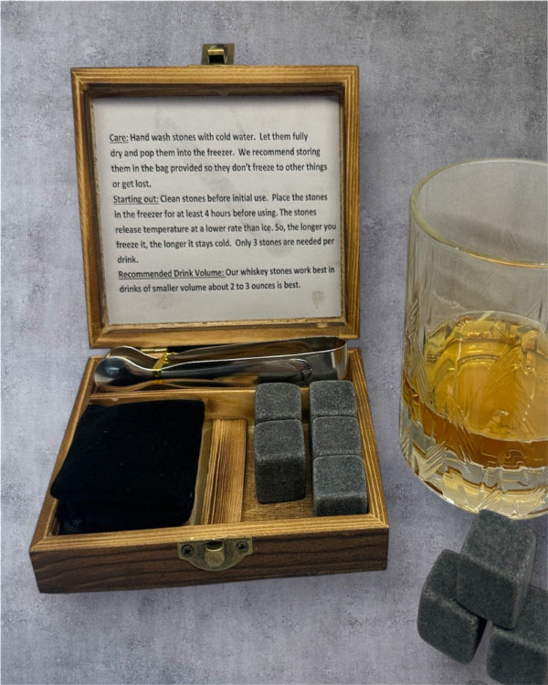 Whiskey stones set with wooden box and glass of whiskey on a gray surface
