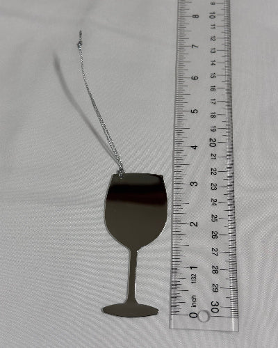 Silver wine glass with chain next to a ruler on a gray background