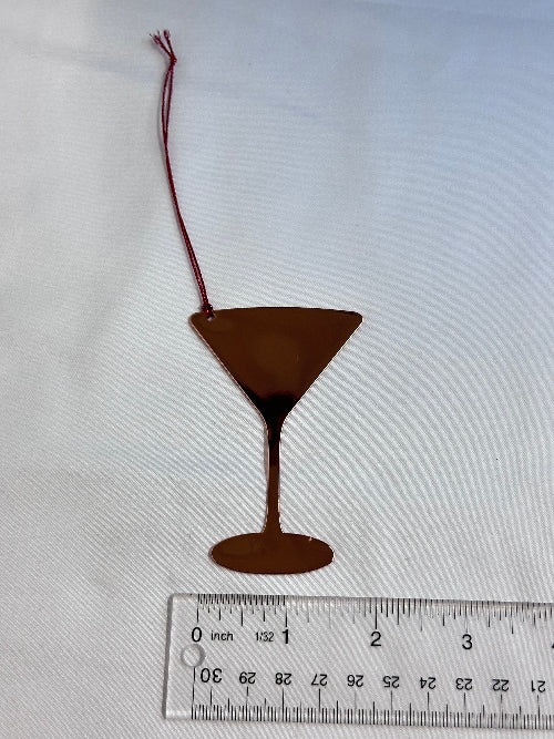 Brown object with a string on a white background, next to a ruler for scale.