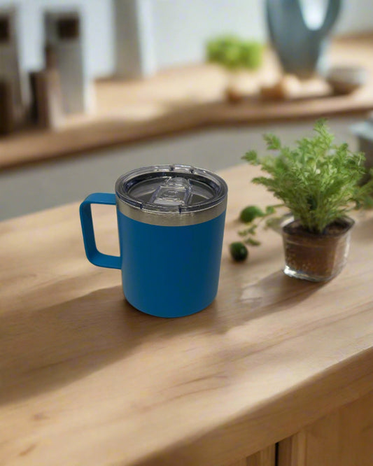 Blue insulated mug on a wooden surface with a plant in the background