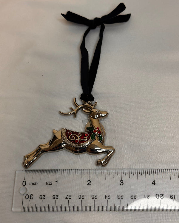 Decorative reindeer charm with black ribbon on a white background with a ruler for scale.