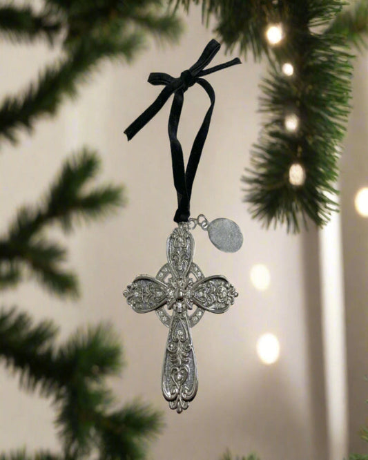 Decorative silver cross ornament with black ribbon on a Christmas tree.