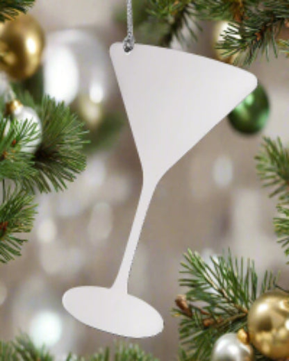 White martini glass ornament hanging on a Christmas tree with gold and green ornaments.
