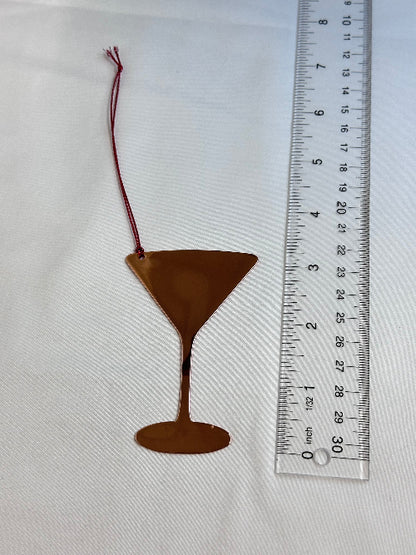 Metallic object with a string next to a ruler on a white background