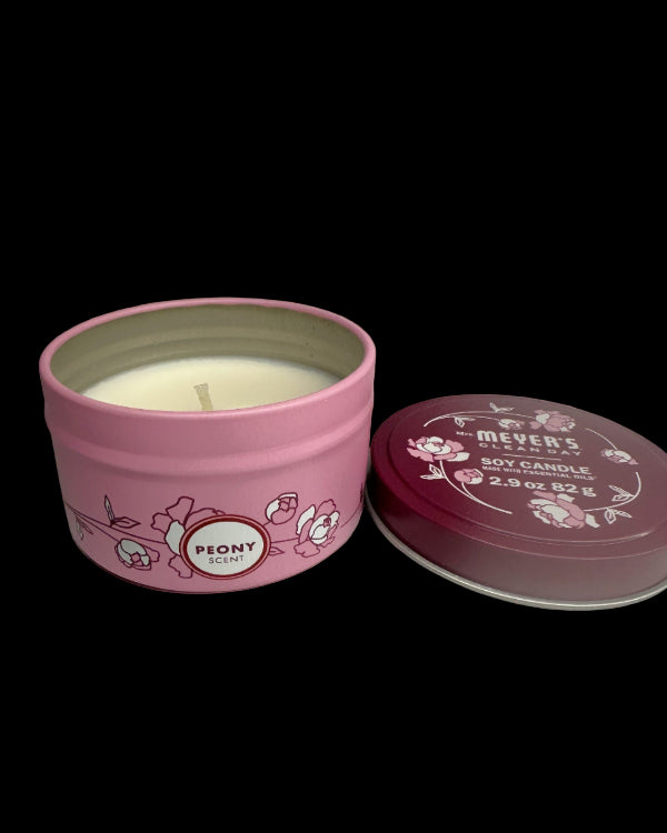 Pink candle tin with 'Peony' scent on a pink background