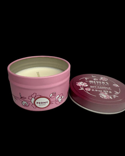 Pink candle tin with 'Peony' scent on a pink background