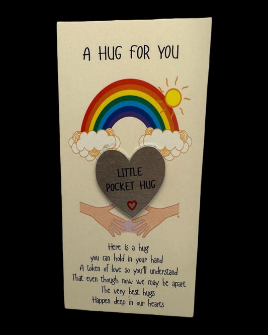 Card with a rainbow, heart, and hands holding a 'Little Pocket Hug' token on a beige background.