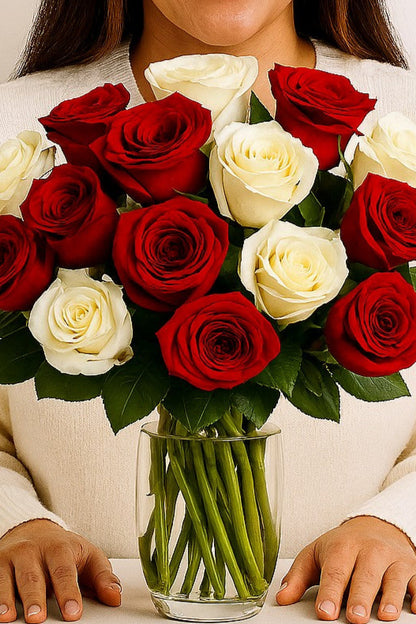 Woman holding a vase of red and white roses against a plain background
