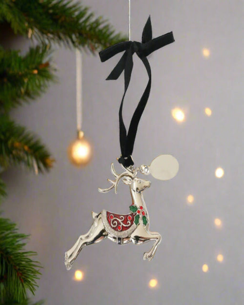 Silver reindeer ornament with a black ribbon on a Christmas tree background