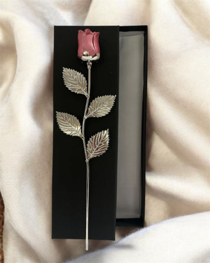 Silver rose brooch with pink rosebud in a black box on a soft fabric background