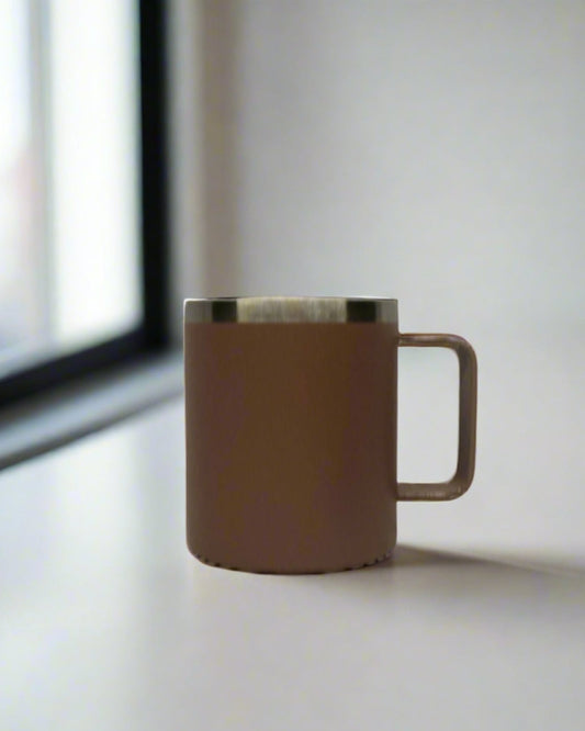Brown pink ceramic mug on a light surface with a window in the background
