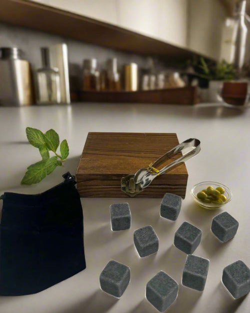 Set of gray stones on a kitchen counter with a wooden box and tongs.